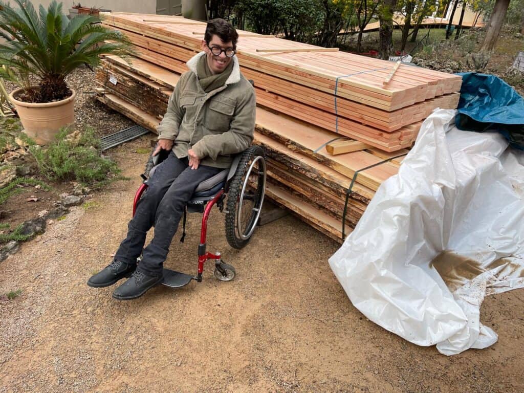 Personne en fauteuil roulant près de bois de construction